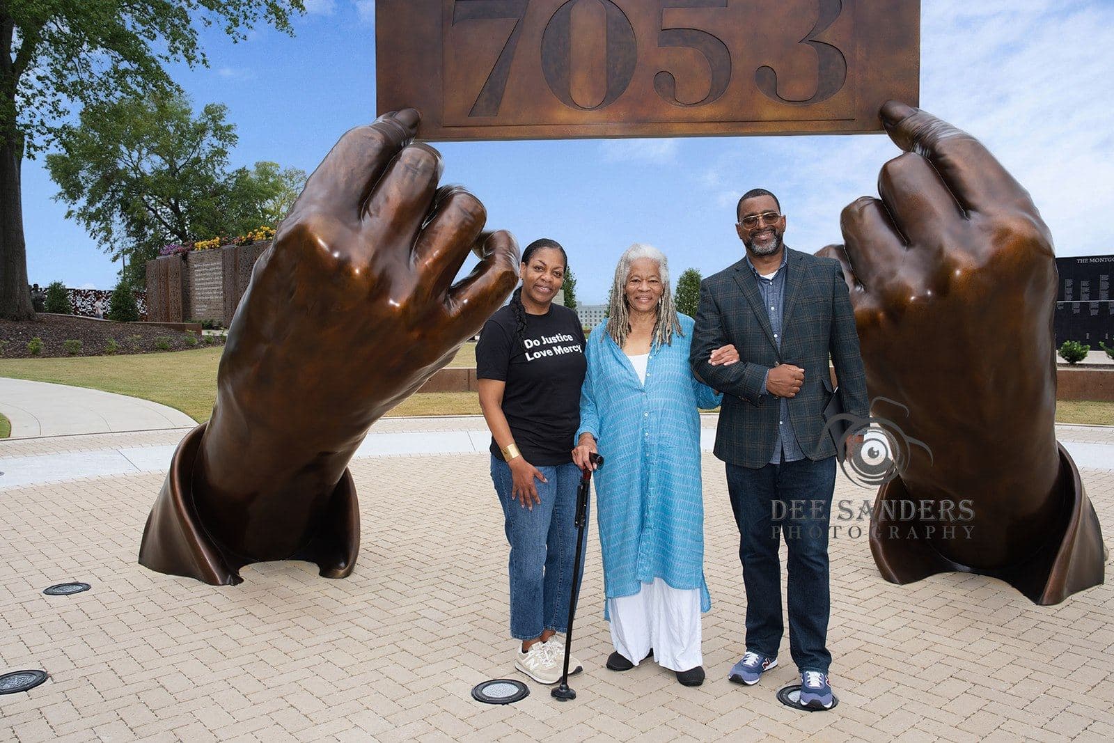 Three attendees posing beneath the 7053 sculpture