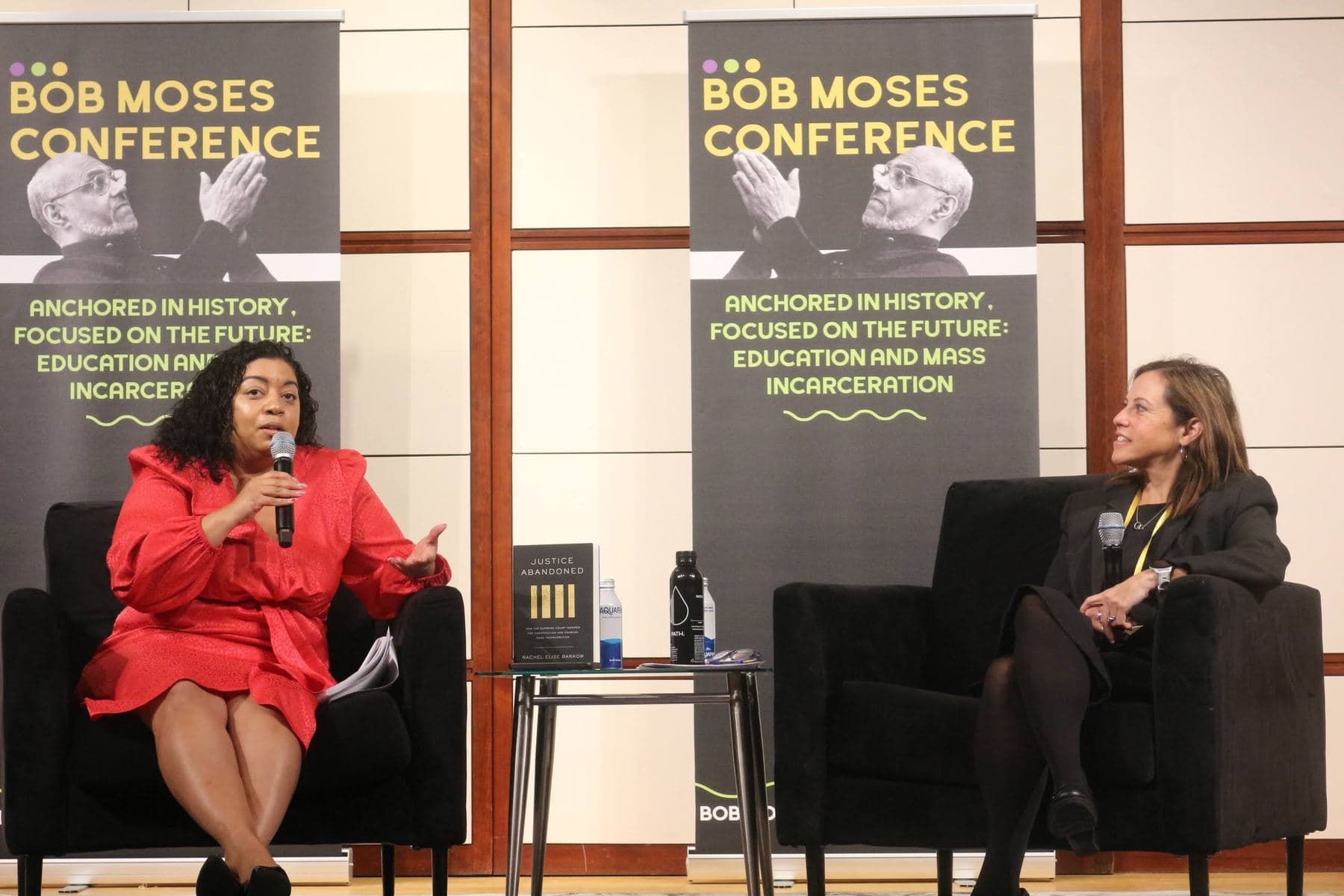 Two speakers in conversation on stage between conference banners